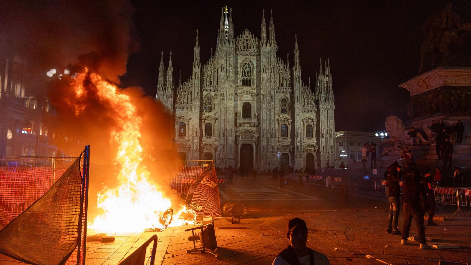 A fire burns following clashes between police and 'Italia in Piazza' protesters in front of the Milan Cathedral in Milan, Italy. Photo: AP via PTI